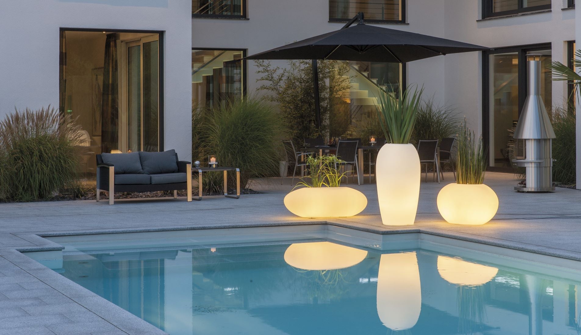 degardo STORUS V weiß, beleuchtet LED RGB vor Villa an Pool während Dämmerung